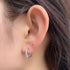 Crystal-adorned silver huggie hoop earring worn on ear, showcasing five-stone design