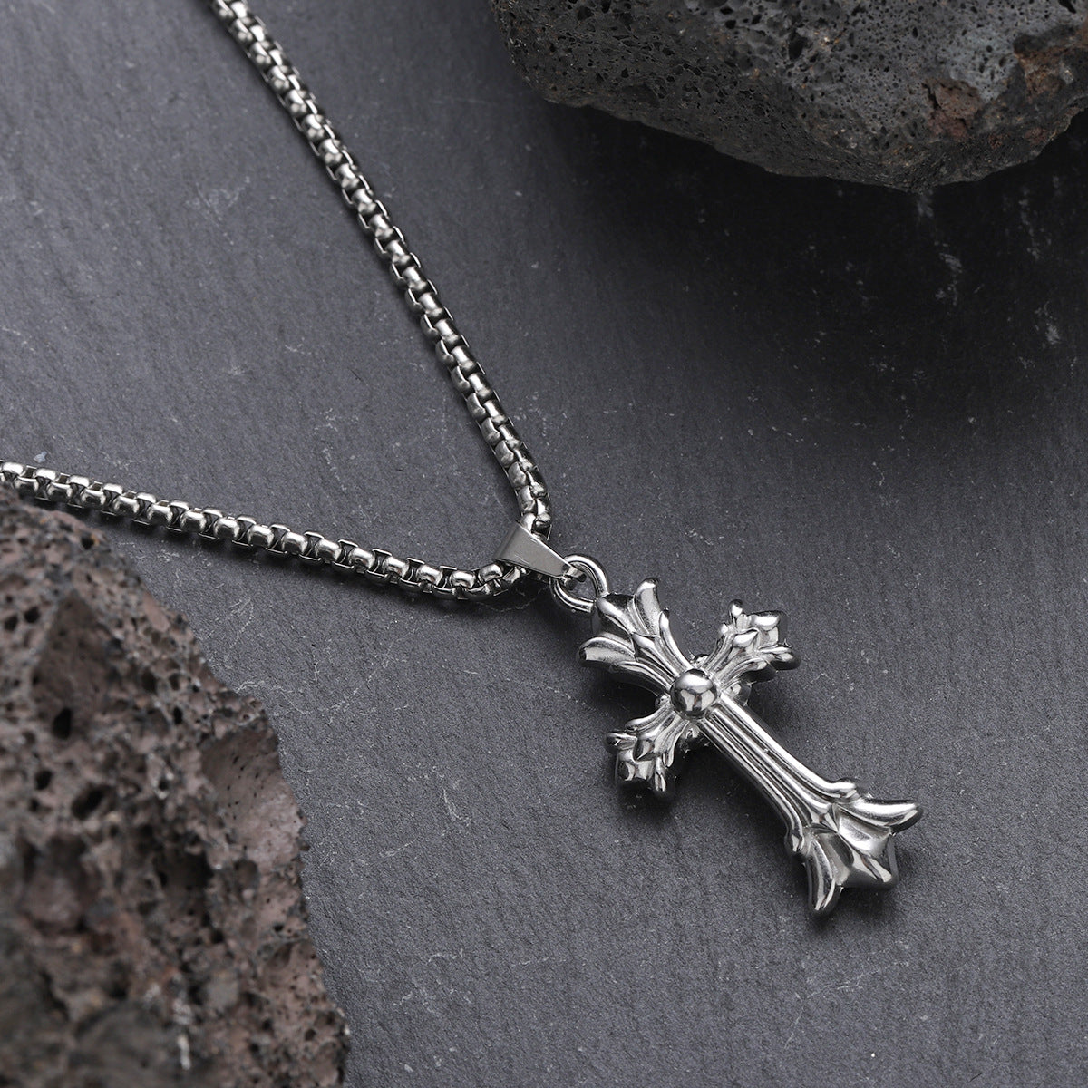 Close-up of silver cross pendant necklace on slate stone background