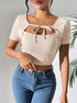 Woman in beige ribbed tie-front crop top posing in natural sunlight.