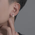 Close-up of engraved silver hoop earring worn on ear, showing profile view