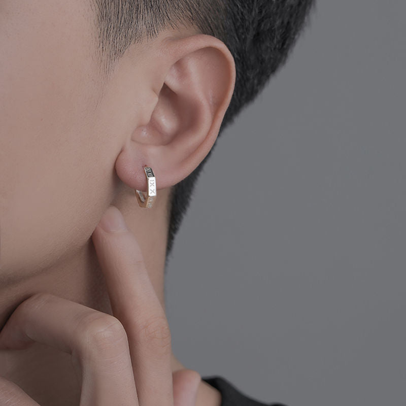 Close-up of engraved silver hoop earring worn on ear, showing profile view