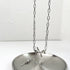 Silver chain necklace with bow charm and key pendant displayed on metal plate. Features oval links and purple gemstone