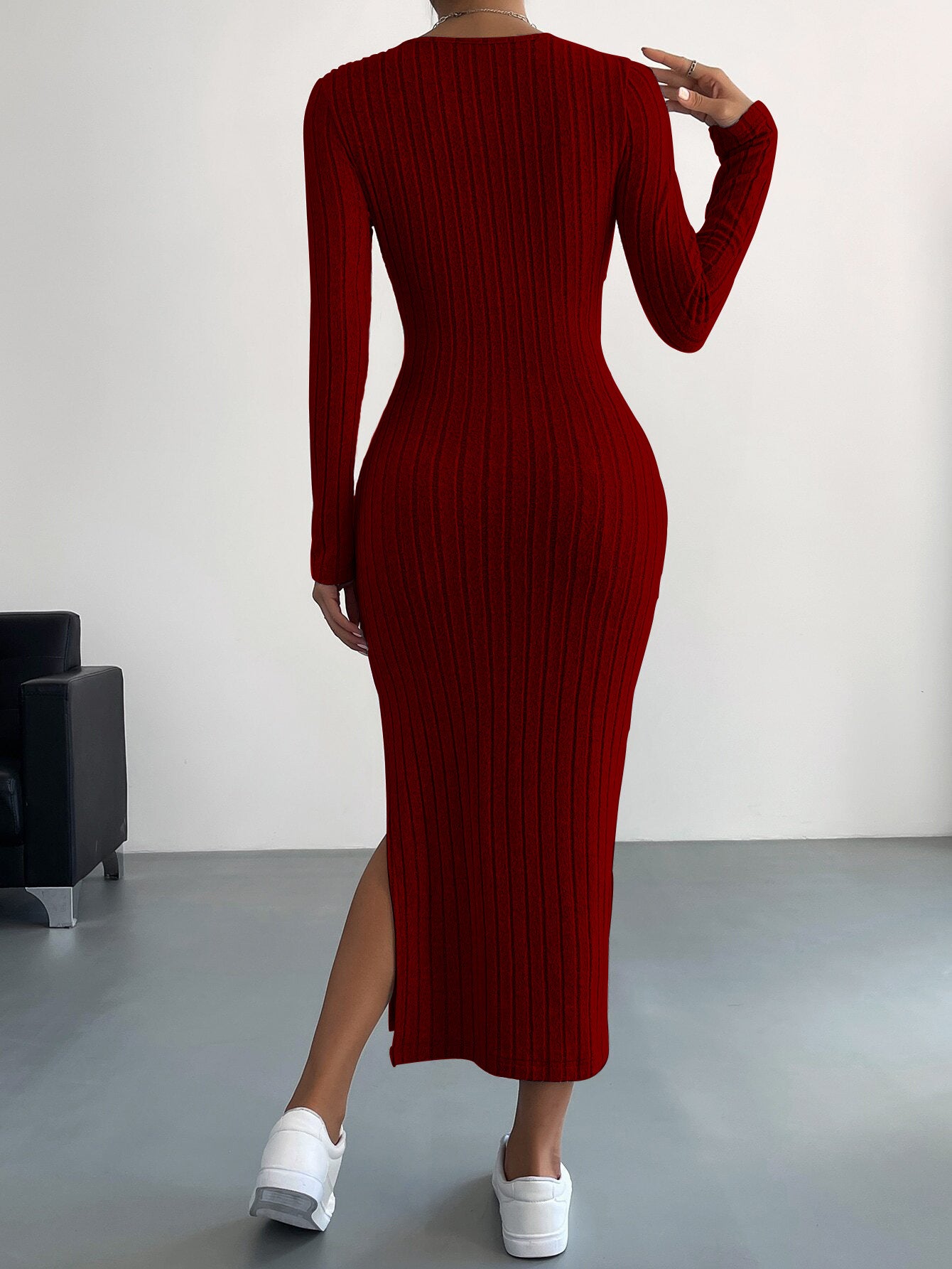 Back view of deep red ribbed midi dress highlighting fitted design and side slit with white sneakers