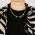 Titanium Steel Cuban chain necklace with yellow smiley charm and crystal snake accent styled on model wearing black t-shirt with striped jacket