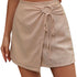 Detail shot of beige wrap skort with gathered fabric and decorative tie closure, textured linen-blend material