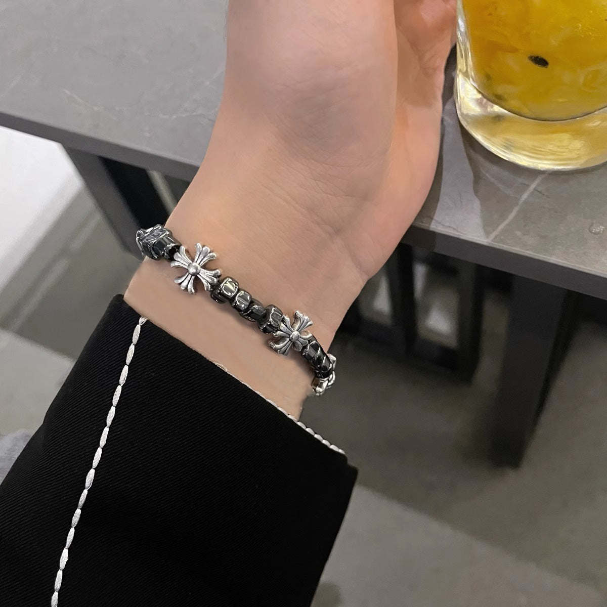 Gothic-style bracelet with black beads and silver cross charms worn on a wrist for a stylish look.