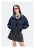 A woman poses in a navy puffer jacket with a plaid lining, a black crop top, a gray pleated skirt, and brown platform boots