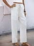 Side angle of white linen pants with front pockets and drawstring waist, paired with a cropped tank top.
