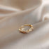 Gold twisted band ring with crystals photographed at angle on silk fabric