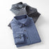 Three stacked flannel shirts in blue and gray patterns. Top shirt shows collar and pocket details