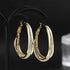 Gold mesh hoop earrings with crystal detailing displayed on black jewelry stand