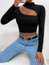 Black long-sleeve crop top with asymmetrical cutout, styled with light blue jeans and gold chain belt