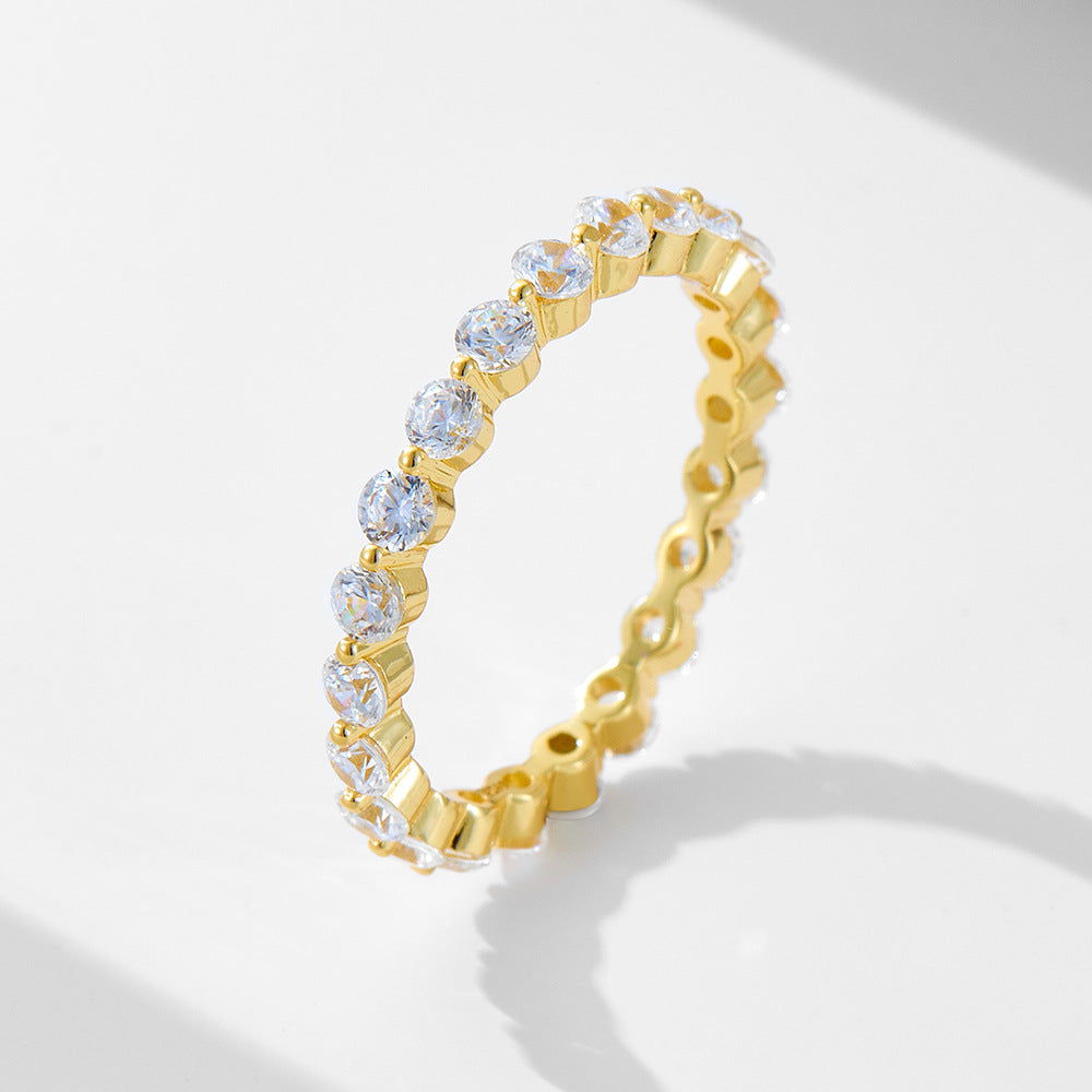 Gold eternity ring with round diamonds in bezel settings creating scalloped edge around entire band, displayed on white surface