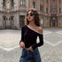 Black one-shoulder top with white trim, styled with dark sunglasses, curly hair, urban street background