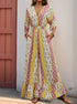 Woman in a patchwork floral jumpsuit with a cinched waist and pockets, wearing gold accessories and brown sandals.