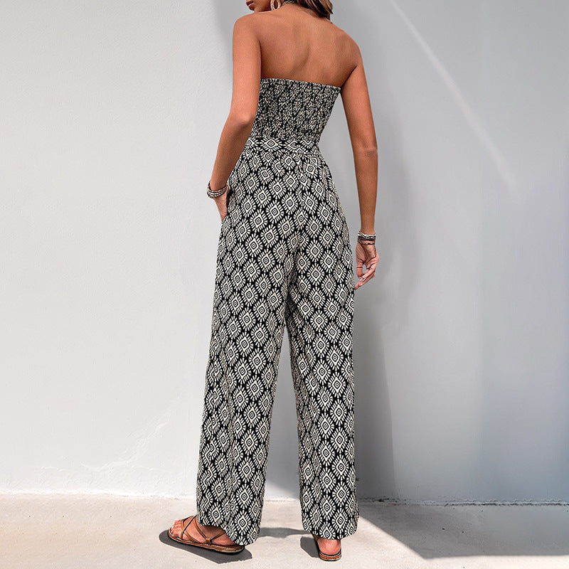 Back view of a woman in a strapless geometric jumpsuit, showing the fitted bodice and flowing wide-leg pants.