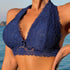 A woman wearing a navy blue lace bralette with deep V-neckline and detailed floral embroidery