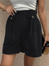 Black high-waisted shorts with decorative buttons, white tank, and delicate gold jewelry
