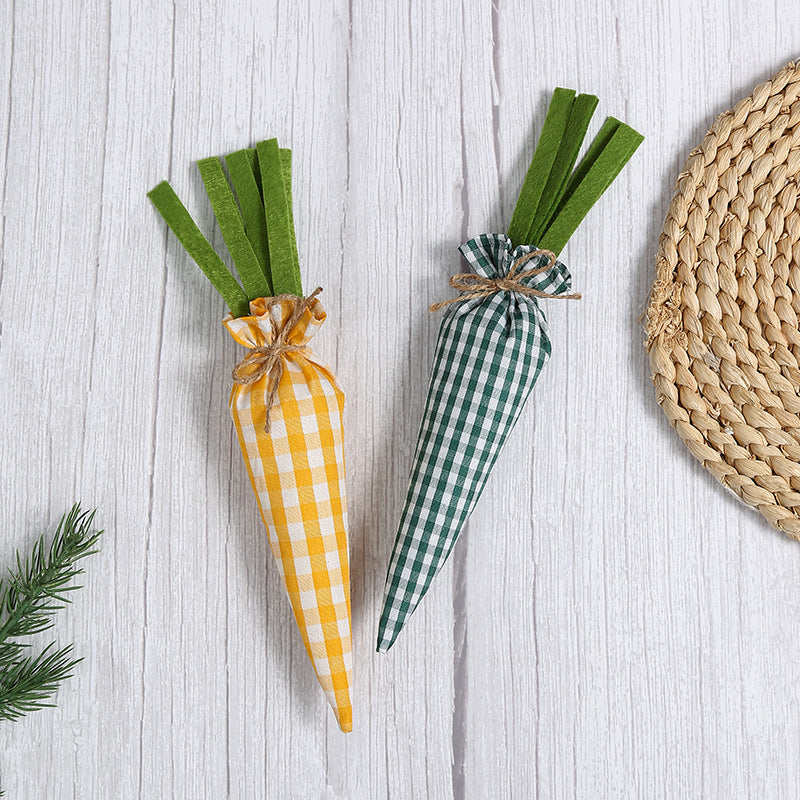 Two fabric carrots, one in yellow gingham and one in green gingham, placed on a white wooden surface with a woven mat nearby.