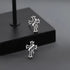 Cross stud earrings displayed on black geometric platform, showcasing detailed design
