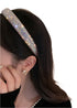  Close-up of a woman wearing a glittering rhinestone headband with a multicolor shimmer, styled with pearl accessories.