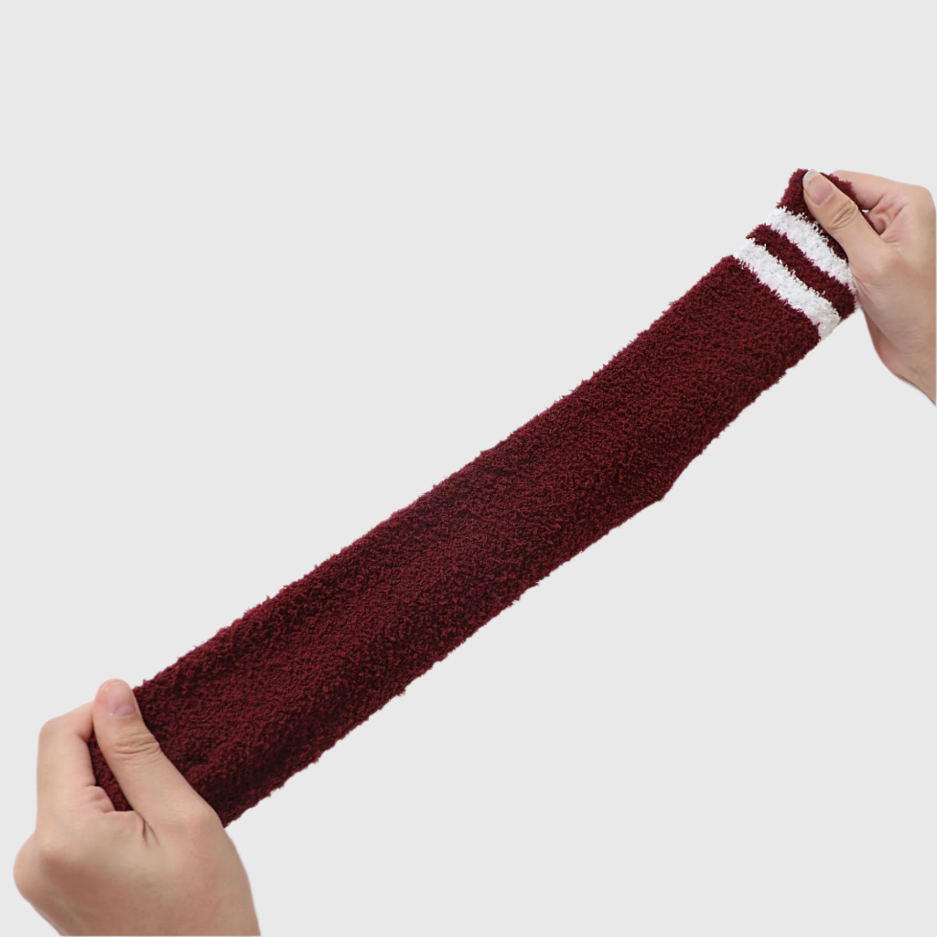 Hands stretching burgundy fluffy sock lengthwise to show flexibility and comfort fit