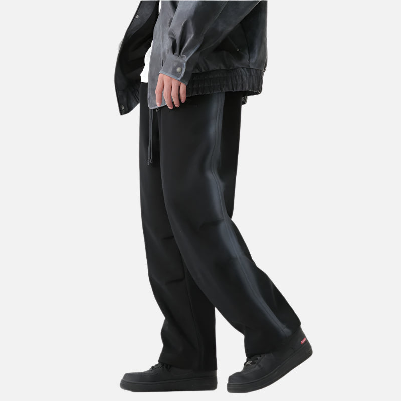 Angled side view of black wide-leg pants showcasing their relaxed fit and slight sheen