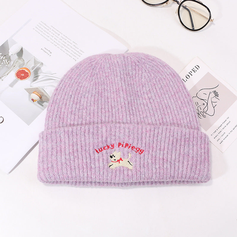 Lavender knit beanie with embroidered white puppy logo on styled product display