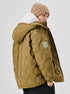A man in beige knit beanie and olive puffer jacket with white hoodie, photographed from side angle against white background