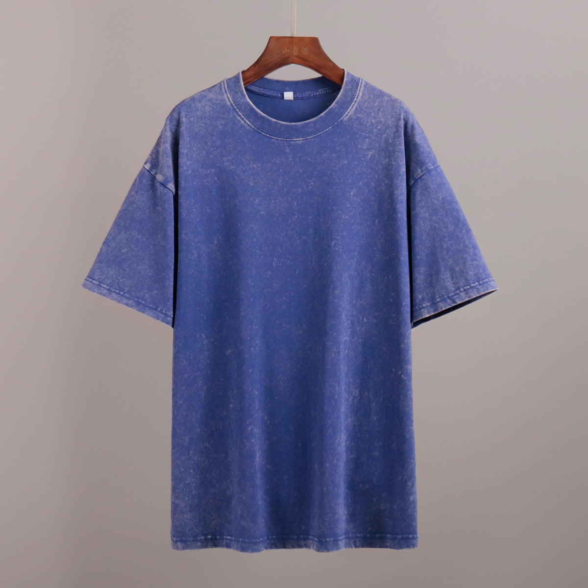 Blue t-shirt on a hanger against a gray background