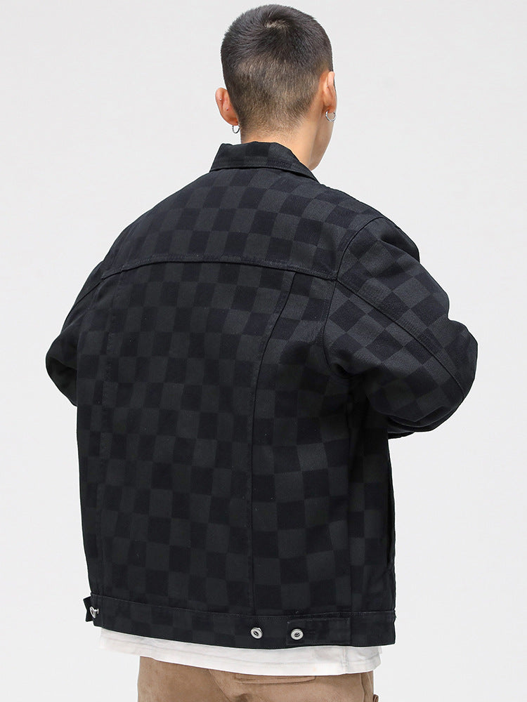 A model is showing the quilted lining of a black checkered jacket over white graphic tee and tan pants against white backdrop
