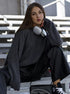 Woman wearing grey knit sweater with silver headphones around neck against geometric background
