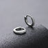 Detail shot of zirconium pavé silver hoop earrings on black surface
