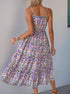 A back view of a woman in a floral spaghetti strap dress with a striped bodice detail, highlighting the ruffled tiers and adjustable straps.