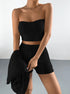 Strapless black ribbed knit two-piece set featuring crop top and high-waisted shorts, accessorized with chain necklace