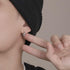Chain-design hoop earring modeled on ear with black beanie.