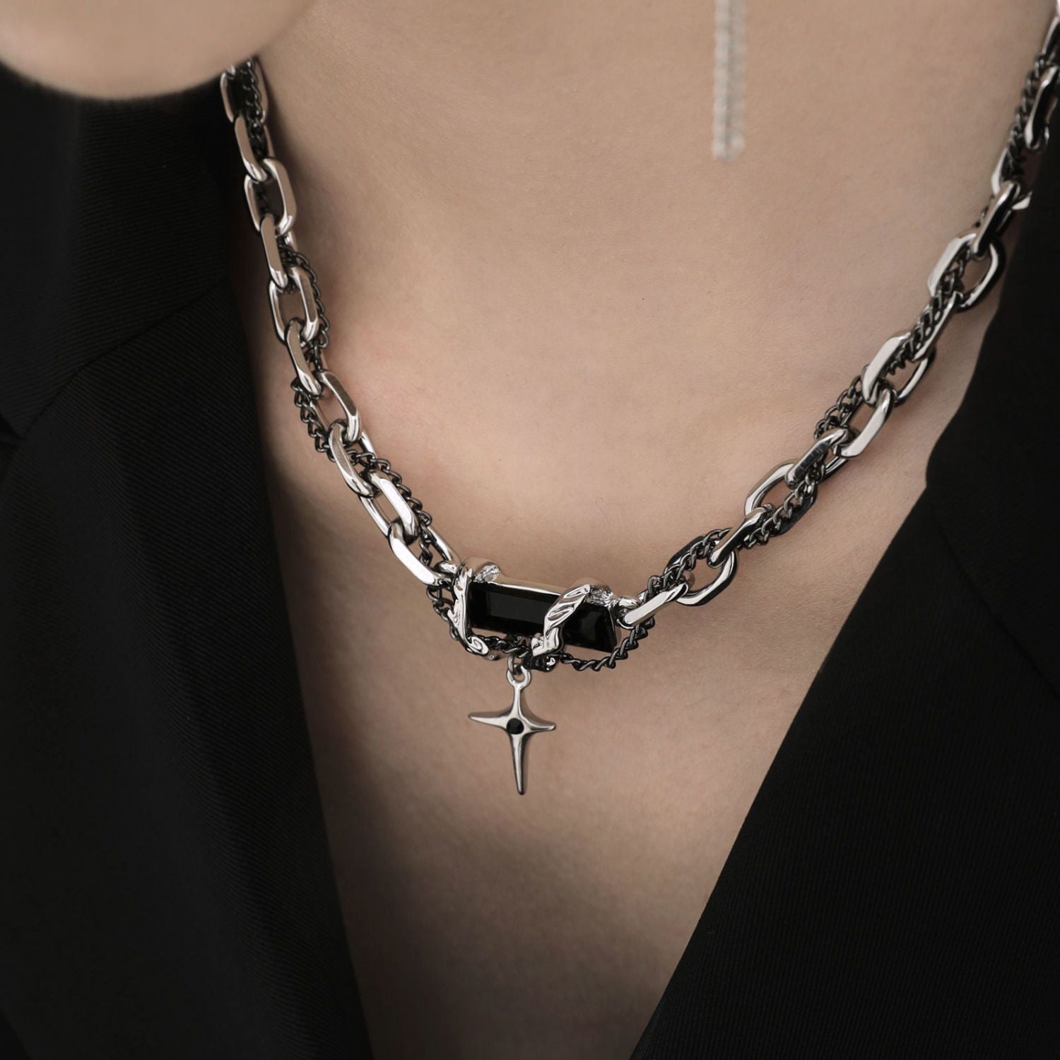 Close-up of silver chain necklace with black stone and star pendant