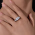 A woman's hand modeling silver oval diamond engagement ring with pave accents against neutral skin tone