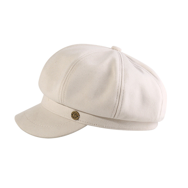 White newsboy cap with small metal emblem shown in product photo against white background