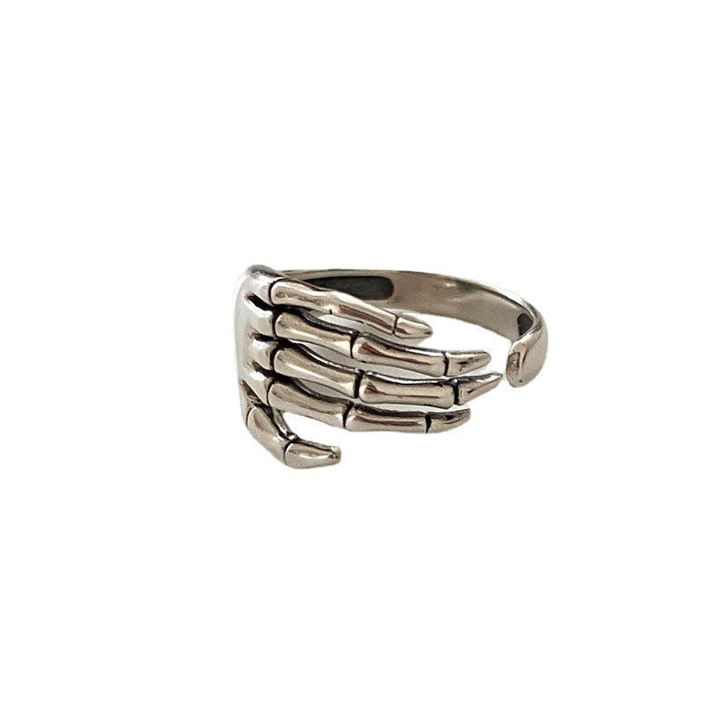 Close-up of a silver skeleton hand ring against a white background, showcasing its adjustable open-ended design