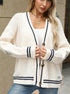 White cable knit cardigan with navy trim, layered over white tank for classic preppy style