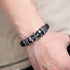 Black and silver cross bracelet worn on a wrist, featuring textured metallic accents.