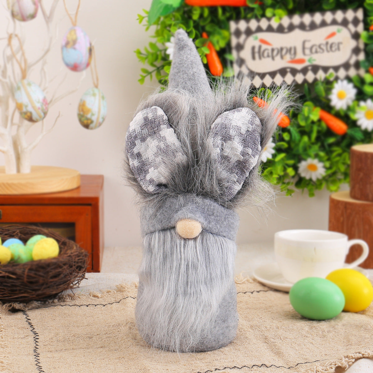 Close-up of a gray Easter gnome with a long beard, soft plush body, and bunny ears, standing on a rustic table with Easter-themed decor.