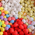 Close-up of colorful mini speckled eggs in white, yellow, red, blue, and purple, arranged in a basket.