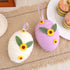 Two textured Easter eggs in white and purple with sunflowers and leaves, displayed on a rustic table, each measuring 13cm x 10cm.