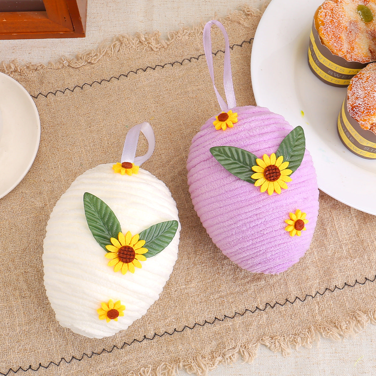 Two textured Easter eggs in white and purple with sunflowers and leaves, displayed on a rustic table, each measuring 13cm x 10cm.