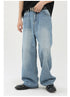 Close-up of light wash wide-leg jeans featuring a 'NOT' belt buckle, styled with black top and patent leather shoes