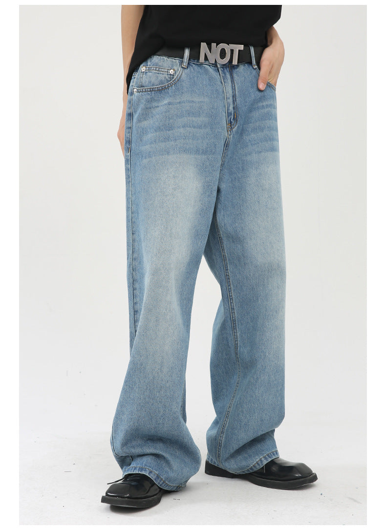 Side view of relaxed fit light wash denim jeans with straight wide legs, worn with black t-shirt and shoes on white background