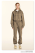 Model in olive loungewear with cropped hoodie and joggers. Accessorized with headphones and cream sneakers