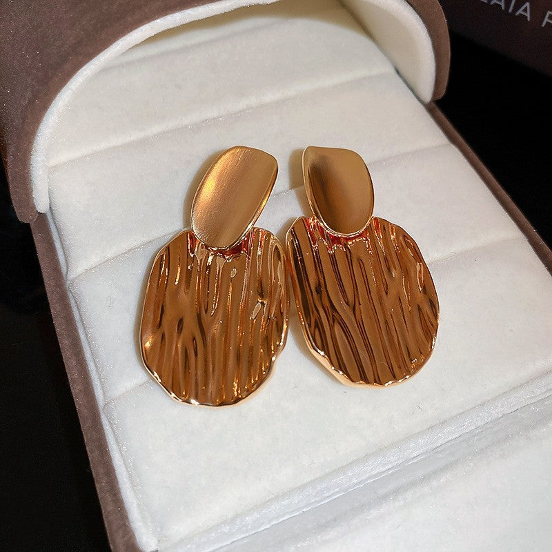 Textured Gold Statement Earrings – Unique gold earrings featuring an organic, woodgrain-like texture, displayed in a velvet jewelry box